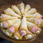 Golden puff pastry cream horns filled with fluffy meringue cream, dusted with powdered sugar