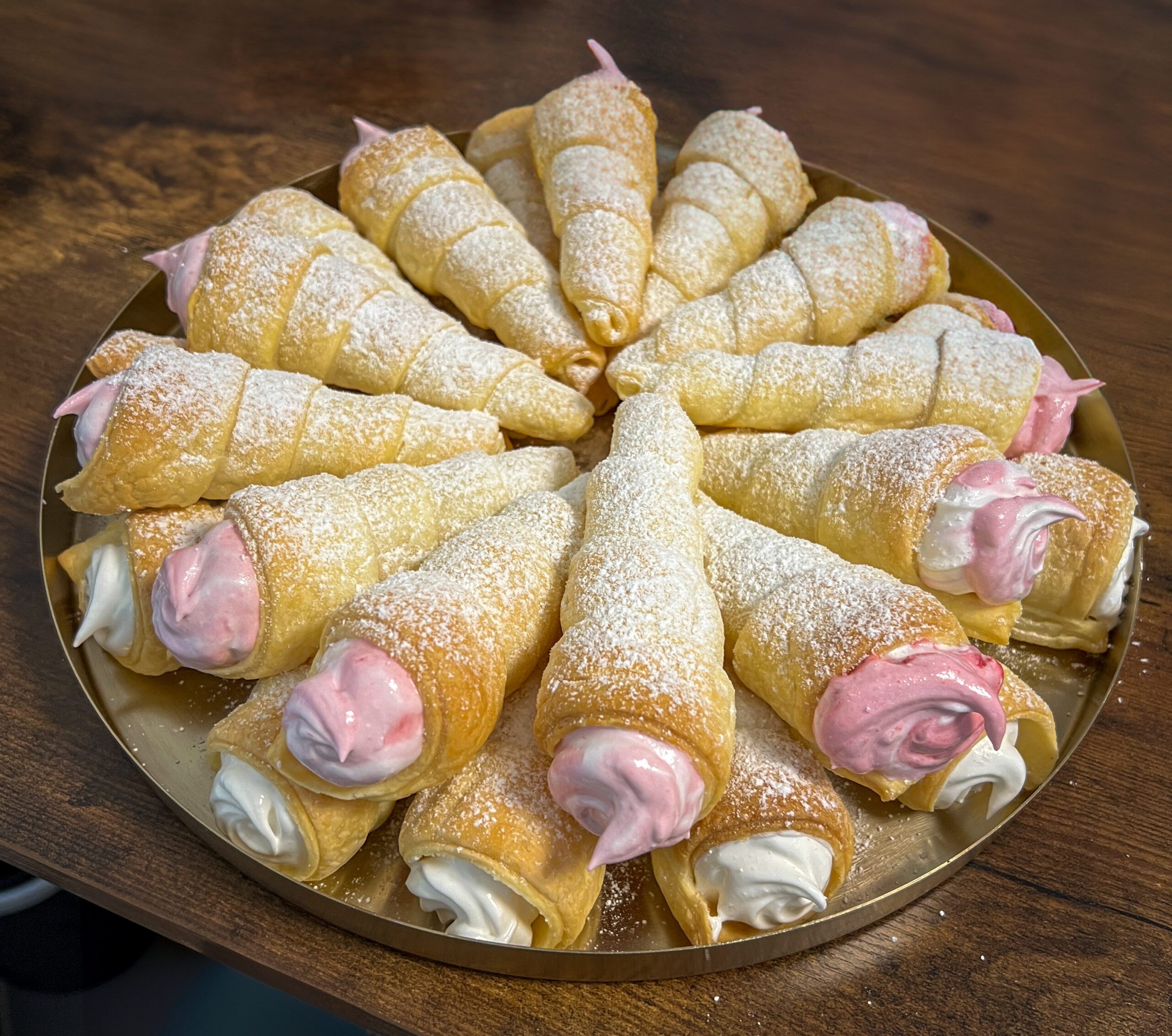 Golden puff pastry cream horns filled with fluffy meringue cream, dusted with powdered sugar